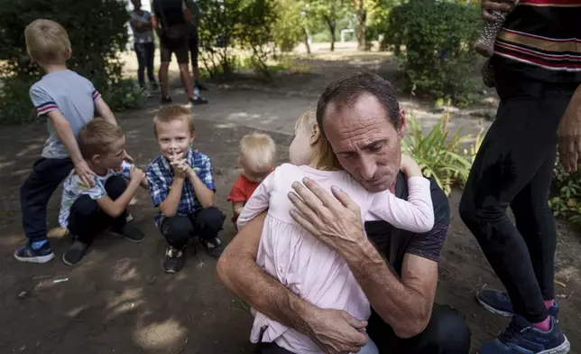 A father hugs his daughter, with his other children nearby, as the family waits to be evacuated in Pokrovsk, Donetsk region, Ukraine, Aug. 23, 2024. (AP Photo/Evgeniy Maloletka)