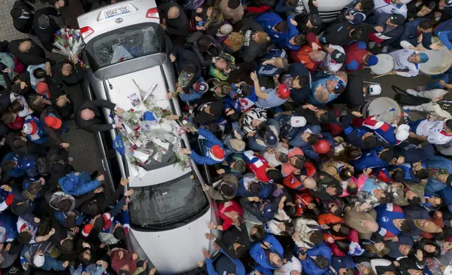 Bouquets of flowers are placed on the rooftop of the hearse transporting the remains of Nacional soccer player Juan Izquierdo, in Montevideo, Uruguay, Aug. 29, 2024. Izquierdo died at a Brazilian hospital after collapsing on the pitch during a Copa Libertadores soccer match between Nacional and Sao Paulo. (AP Photo/Matilde Campodonico)