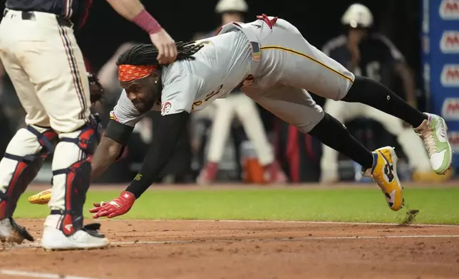 Pittsburgh Pirates' Oneil Cruz, right, begins his slide past Cleveland Guardians catcher Austin Hedges, left, to score in the fifth inning of a baseball game Friday, Aug. 30, 2024, in Cleveland. (AP Photo/Sue Ogrocki)