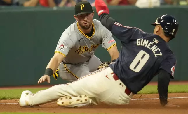 Pittsburgh Pirates second baseman Jared Triolo, left, reaches for sliding Cleveland Guardians' Andres Gimenez (0) at third base but can't make the tag as Gimenez is safe in the fourth inning of a baseball game Friday, Aug. 30, 2024, in Cleveland. (AP Photo/Sue Ogrocki)