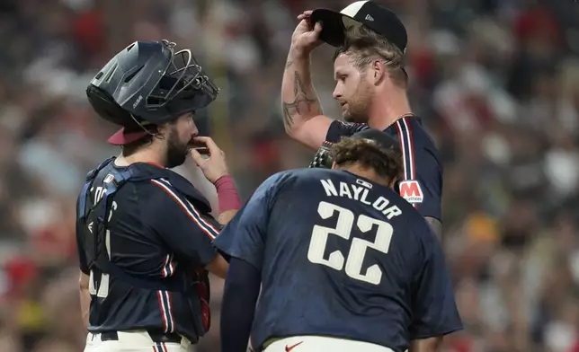 Cleveland Guardians catcher Austin Hedges, left, and first baseman Josh Naylor (22) meet with starting pitcher Ben Lively, right, in the fourth inning of a baseball game against the Pittsburgh Pirates Friday, Aug. 30, 2024, in Cleveland. (AP Photo/Sue Ogrocki)