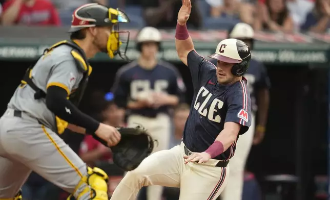 Cleveland Guardians' Lane Thomas, right, begins his slide to score behind Pittsburgh Pirates catcher Yasmani Grandal, left, in the first inning of a baseball game Friday, Aug. 30, 2024, in Cleveland. (AP Photo/Sue Ogrocki)