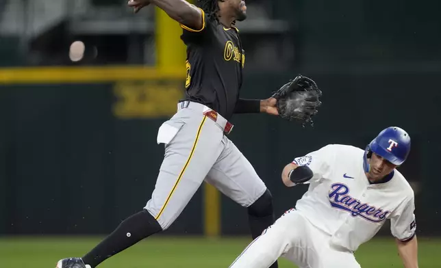 Pittsburgh Pirates shortstop Oneil Cruz throws to first to complete the double play against Texas Rangers' Jonah Heim after forcing Corey Seager, right, at second in the third inning of a baseball game, Wednesday, Aug. 21, 2024, in Arlington, Texas. (AP Photo/Tony Gutierrez)