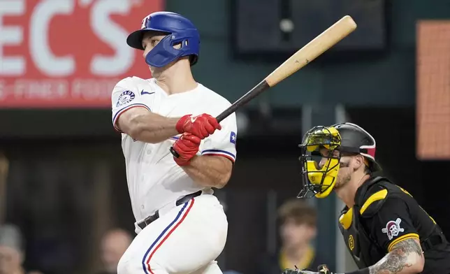 Texas Rangers' Wyatt Langford follows through on a run-scoring single as Pittsburgh Pirates catcher Yasmani Grandal, right, looks on in the ninth inning of a baseball game, Wednesday, Aug. 21, 2024, in Arlington, Texas. (AP Photo/Tony Gutierrez)