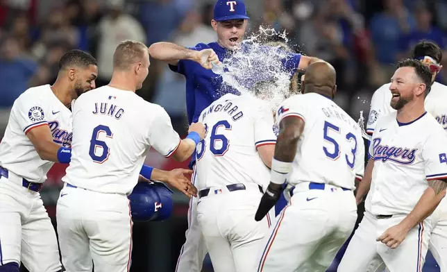 Texas Rangers' Cody Bradford pours water on Wyatt Langford (36) as the team celebrates Langford's run-scoring single in the ninth inning of a baseball game against the Pittsburgh Pirates, Wednesday, Aug. 21, 2024, in Arlington, Texas. (AP Photo/Tony Gutierrez)