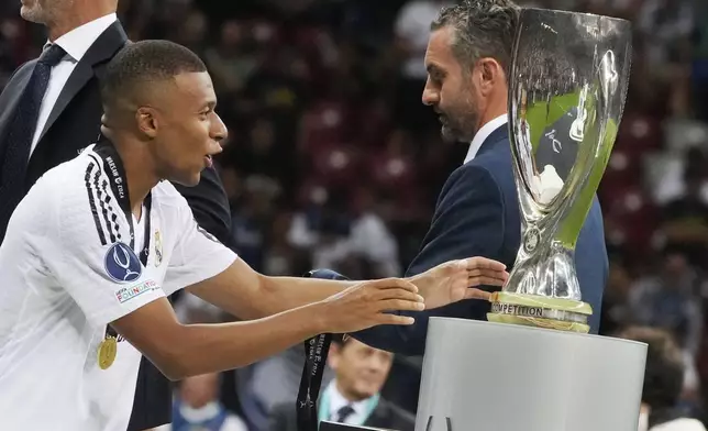 Real Madrid's Kylian Mbappe touches the trophy during the medal ceremony for the UEFA Super Cup Final soccer match between Real Madrid and Atalanta at the Narodowy stadium in Warsaw, Poland, Wednesday, Aug. 14, 2024. (AP Photo/Czarek Sokolowski)