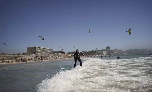 A member of Surf Church surfs before a worship service in Matosinhos beach in the suburbs of Porto, Portugal, Sunday, Aug. 18, 2024. (AP Photo/Luis Andres Henao)