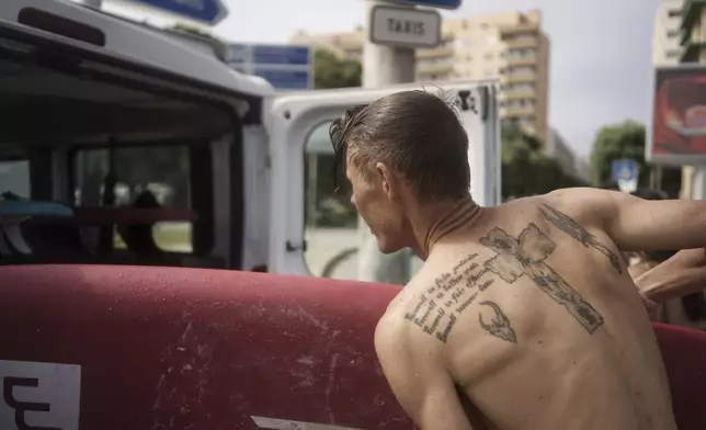 Surf Church member Andries Louw stows a surfboard in a church van in Porto, Portugal on Sunday, Aug. 18, 2024. (AP Photo/Luis Andres Henao)