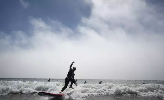 Surf Church member Zakharii Yarovyi, from Ukraine, surfs before a worship service in Matosinhos beach in the suburbs of Porto, Portugal on Sunday, Aug. 18, 2024. (AP Photo/Luis Andres Henao)