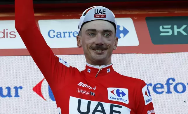 Brandon McNulty, of the United States, wearing the overall leader red jersey, gestures on the podium after winning the first stage of the tour of Spain, La Vuelta, cycling race, an individual time trial with start in Lisbon and finish in Oeiras, Portugal, Saturday, Aug. 17, 2024. (AP Photo/Pedro Rocha)