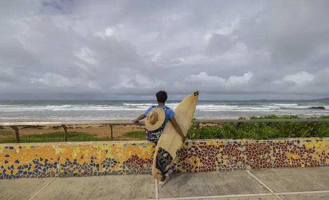 A surfer prepares to enter the water before the passage of Tropical Storm Ernesto at La Pared beach in Luquillo, Puerto Rico, Tuesday, Aug. 13, 2024. (AP Photo/Alejandro Granadillo)