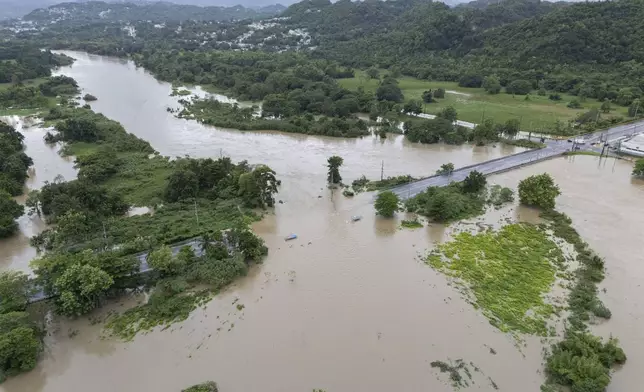 La Plata river floods a road after Tropical Storm Ernesto passed through Toa Baja, Puerto Rico, Wednesday, Aug. 14, 2024. (AP Photo/Alejandro Granadillo)