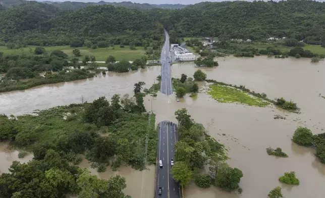 La Plata river overflows onto a road after Tropical Storm Ernesto passed through Toa Baja, Puerto Rico, Wednesday, Aug. 14, 2024. (AP Photo/Alejandro Granadillo)