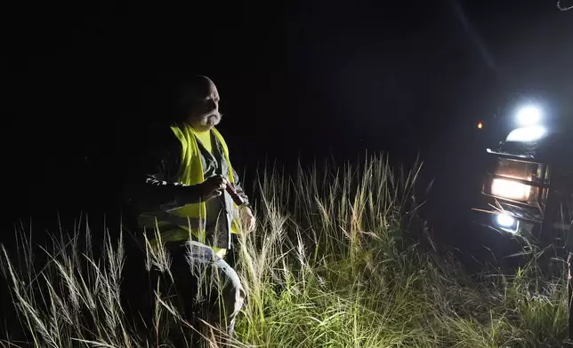 Thomas Aycock, a contractor with the Florida Fish and Wildlife Conservation Commission, heads back to his truck after checking out a marker along a levy as he searches for invasive Burmese pythons, Tuesday, Aug. 13, 2024, in the Florida Everglades. (AP Photo/Wilfredo Lee)