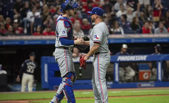 Texas Rangers' Jonah Heim, left, congratulates Kirby Yates, right, at the end of a baseball game against the Cleveland Guardians in Cleveland, Friday, Aug. 23, 2024. (AP Photo/Phil Long)