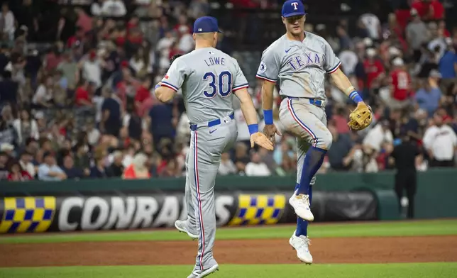 Texas Rangers' Nathaniel Lowe (30) celebrates with Josh Jung, right, at the end of a baseball game against the Cleveland Guardians in Cleveland, Friday, Aug. 23, 2024. (AP Photo/Phil Long)