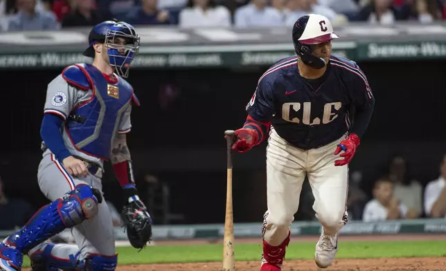 Cleveland Guardians' Bo Naylor, right, watches his RBI single off Texas Rangers starting pitcher Nathan Eovaldi as Rangers catcher Jonah Heim, left, also watches during the fourth inning of a baseball game in Cleveland, Friday, Aug. 23, 2024. (AP Photo/Phil Long)