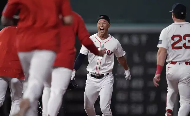 Boston Red Sox's Rob Refsnyder, center, celebrates after his winning RBI single in the 10th inning of a baseball game against the Texas Rangers at Fenway Park, Monday, Aug. 12, 2024, in Boston. (AP Photo/Charles Krupa)