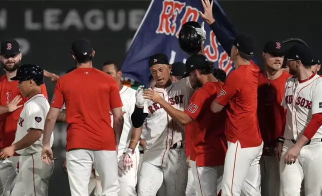 Boston Red Sox's Rob Refsnyder, center, celebrates after his winning RBI single in the 10th inning of a baseball game against the Texas Rangers at Fenway Park, Monday, Aug. 12, 2024, in Boston. (AP Photo/Charles Krupa)