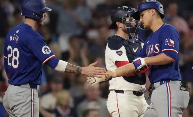 Texas Rangers' Corey Seager, right, is congratulated by Jonah Heim (28) after his two-run home run off Boston Red Sox pitcher Bailey Horn during the seventh inning of a baseball game at Fenway Park, Monday, Aug. 12, 2024, in Boston. (AP Photo/Charles Krupa)