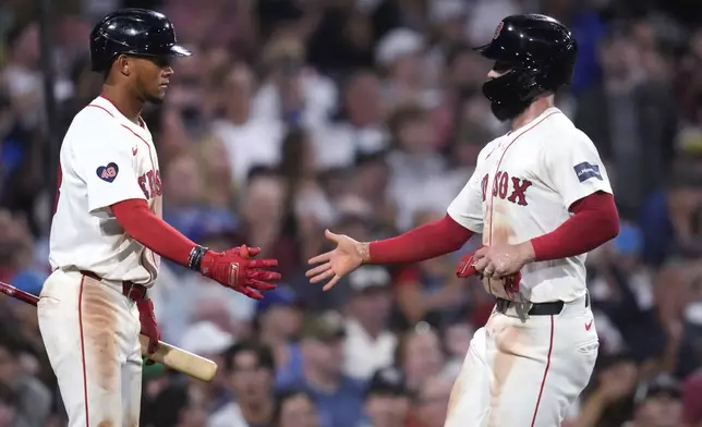 Boston Red Sox's Connor Wong, right, is congratulated by Ceddanne Rafaela, left, after scoring on a Nick Sogard sacrifice fly during the fourth inning of a baseball game against the Texas Rangers at Fenway Park, Monday, Aug. 12, 2024, in Boston. (AP Photo/Charles Krupa)