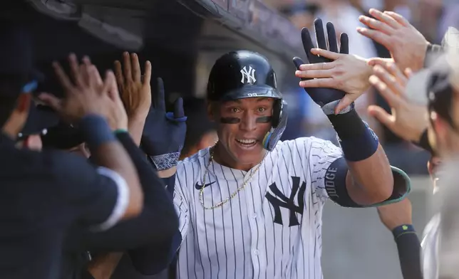 New York Yankees' Aaron Judge is greeted in the dugout after hitting a home run in the seventh inning of a baseball game against the Texas Rangers, Sunday, Aug. 11, 2024, in New York. (AP Photo/John Munson)