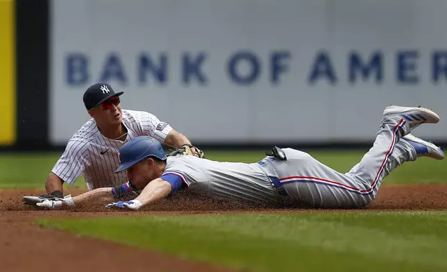 Texas Rangers' Corey Seager is tagged out by New York Yankees shortstop Anthony Volpe at second base during the first inning of a baseball game Sunday, Aug. 11, 2024, in New York. (AP Photo/John Munson)