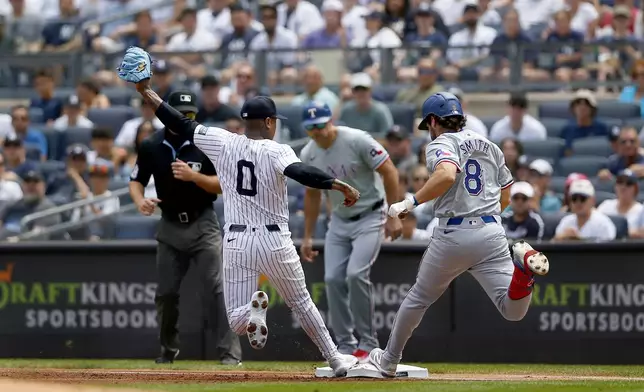 New York Yankees pitcher Marcus Stroman, left, gets to first base in time to retire Texas Rangers' Josh Smith in the first inning of a baseball game Sunday, Aug. 11, 2024, in New York. (AP Photo/John Munson)