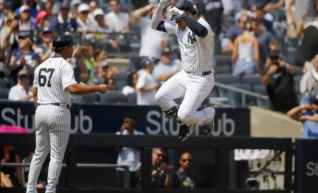 New York Yankees third base coach Luis Rojas (67) congratulates Juan Soto after his home run in the third inning of a baseball game against the Texas Rangers, Sunday, Aug. 11, 2024, in New York. (AP Photo/John Munson)