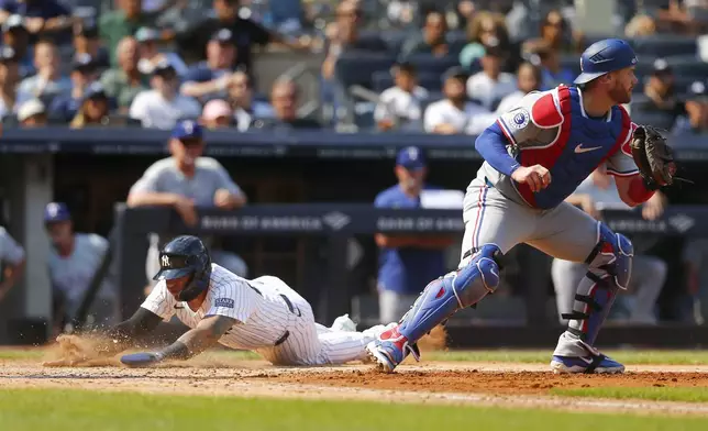 New York Yankees' Gleyber Torres dives across the plate for a run as Texas Rangers catcher Carson Kelly catches the late throw in the sixth inning during a baseball game Sunday, Aug. 11, 2024, in New York. (AP Photo/John Munson)