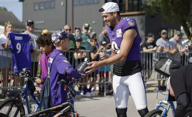 Baltimore Ravens kicker Justin Tucker signs autographs during an NFL football joint training camp practice with the Green Bay Packers Thursday, Aug. 22, 2024, in Green Bay, Wis. (AP Photo/Matt Ludtke)