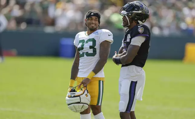 Green Bay Packers cornerback Jaire Alexander (23) and Baltimore Ravens quarterback Lamar Jackson (8) share a laugh during an NFL football joint training camp practice Thursday, Aug. 22, 2024, in Green Bay, Wis. (AP Photo/Matt Ludtke)