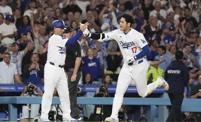 Los Angeles Dodgers designated hitter Shohei Ohtani (17) greets third base coach Dino Ebel as he runs the bases after hitting a grand slam during the ninth inning of a baseball game against the Tampa Bay Rays in Los Angeles, Friday, Aug. 23, 2024. The Dodgers won 7-3. Will Smith, Tommy Edman, and Max Muncy also scored. (AP Photo/Ashley Landis)