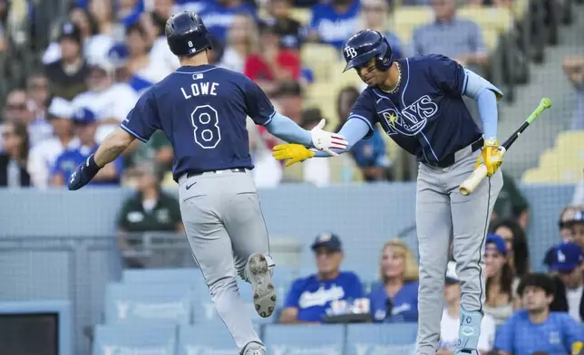 Tampa Bay Rays designated hitter Brandon Lowe (8) celebrates with Christopher Morel after scoring off of a single hit by Junior Caminero during the first inning of a baseball game against the Los Angeles Dodgers in Los Angeles, Saturday, Aug. 24, 2024. (AP Photo/Ashley Landis)