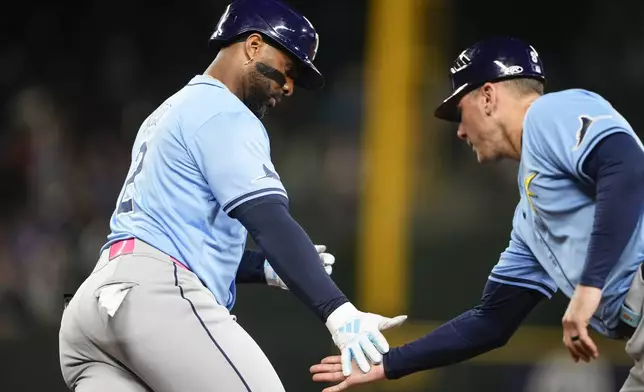 Tampa Bay Rays' Yandy Díaz greets first base coach Michael Johns as he jogs the bases after hitting a home run against the Seattle Mariners during the eighth inning of a baseball game, Tuesday, Aug. 27, 2024, in Seattle. (AP Photo/Lindsey Wasson)