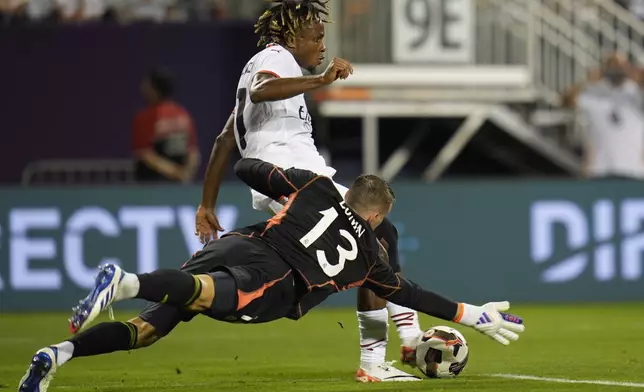 Real Madrid goalkeeper Andriy Lunin dives as Milan forward Samuel Chukwueze passes the ball during the second half of a friendly soccer match Wednesday, July 31, 2024, in Chicago. (AP Photo/Erin Hooley)