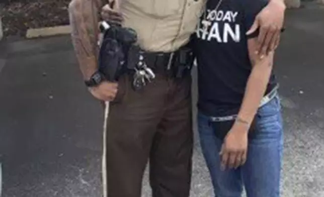 In this undated photo provided by Charlene Jefferson in August 2024, Travis Brown, when he was St. Louis County police officer, stands with Danielle Oliver. Brown, a Ferguson Police officer, suffered a severe brain injury after he was knocked to the ground Friday, Aug. 9, 2024, during a protest in Ferguson, Mo., on the 10th anniversary of the shooting death of Michael Brown. (Charlene Jefferson via AP)