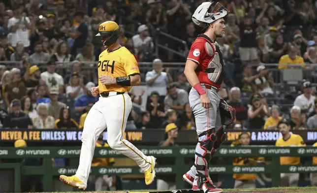 Pittsburgh Pirates catcher Joey Bart scores in front of Cincinnati Reds catcher Tyler Stephenson in the sixth inning of a baseball game, Friday, Aug. 23, 2024, in Pittsburgh. (AP Photo/Barry Reeger)