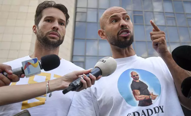 Andrew Tate speaks to media next to his brother Tristan, left, outside the Bucharest Tribunal after being placed under house arrest, in Bucharest, Romania, Thursday, Aug. 22, 2024. A court in Romania's capital on Thursday placed the divisive internet influencer Andrew Tate under house arrest for 30 days, as prosecutors investigate a sprawling new case that involves allegations of human trafficking of minors and sex with a minor. (AP Photo/Alexandru Dobre)