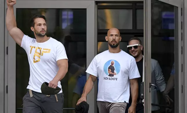 Andrew Tate, center, and his brother Tristan, left, exit the Bucharest Tribunal after being placed under house arrest, in Bucharest, Romania, Thursday, Aug. 22, 2024. A court in Romania's capital on Thursday placed the divisive internet influencer Andrew Tate under house arrest for 30 days, as prosecutors investigate a sprawling new case that involves allegations of human trafficking of minors and sex with a minor. (AP Photo/Alexandru Dobre)