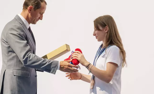 Mihai Covaliu, President of the Romanian Olympic and Sports Committee offers the Olympic games mascot to Romanian gymnast Ana Barbosu after she received the bronze medal for her women's artistic gymnastics individual floor performance at the Paris 2024 Olympics, during a ceremony, in Bucharest, Romania, Friday, Aug. 16, 2024. American gymnast Jordan Chiles called an arbitration panel's decision that dropped her out of the bronze medal position in the floor exercise at the Paris Olympics "unjust" and a "significant blow" in a message posted on social media Thursday. (AP Photo/Vadim Ghirda)