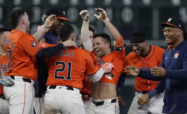 Houston Astros' Jose Altuve (27) is mobbed by his teammates after hitting a walk-off RBI double during the ninth inning of a baseball game against the Kansas City Royals, Friday, Aug. 30, 2024, in Houston. (AP Photo/Kevin M. Cox)