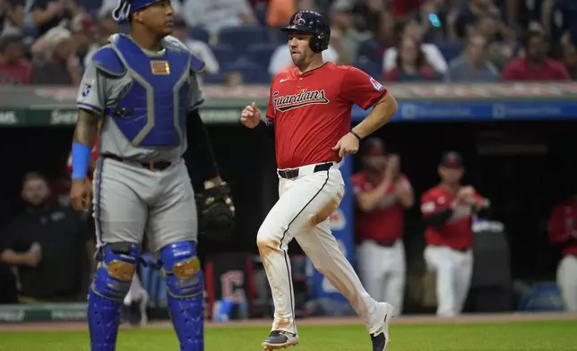 Cleveland Guardians' David Fry, right, scores behind Kansas City Royals catcher Salvador Perez, left, on a single hit by Lane Thomas in the fourth inning of a baseball game Tuesday, Aug. 27, 2024, in Cleveland. (AP Photo/Sue Ogrocki)