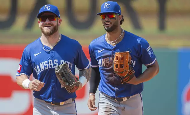 Kansas City Royals' Kyle Isbel, left, laughs with MJ Melendez, right, after congratulating him for his diving catch during the fifth inning of the first game of a baseball doubleheader against the Cleveland Guardians in Cleveland, Monday, Aug. 26, 2024. (AP Photo/Phil Long)