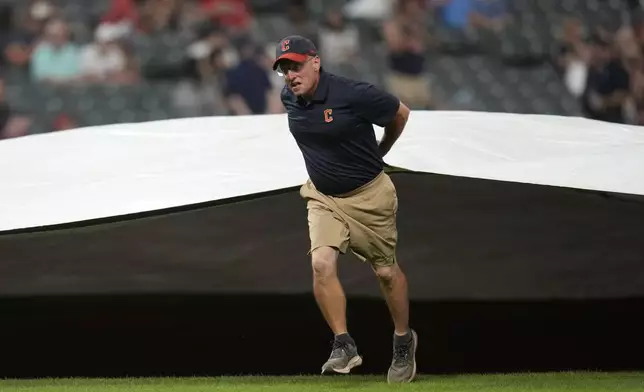 The Cleveland Guardians grounds crew brings out the tarp for a rain delay after the fifth inning of a baseball game between the Kansas City Royals and the Cleveland Guardians Tuesday, Aug. 27, 2024, in Cleveland. (AP Photo/Sue Ogrocki)