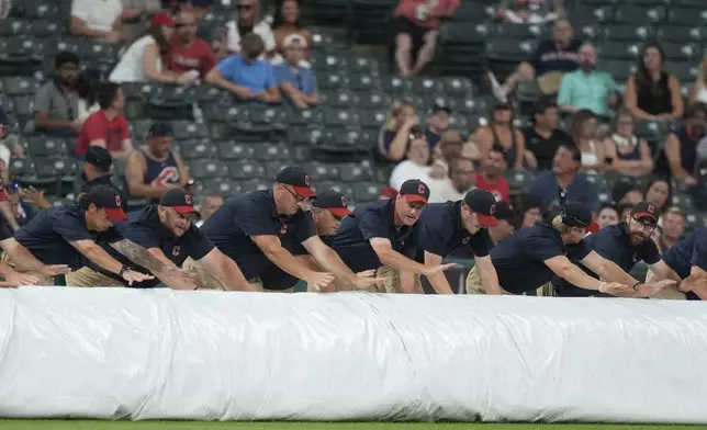 The Cleveland Guardians grounds crew rolls out the tarp for a rain delay after the fifth inning of a baseball game between the Kansas City Royals and the Cleveland Guardians, Tuesday, Aug. 27, 2024, in Cleveland. (AP Photo/Sue Ogrocki)