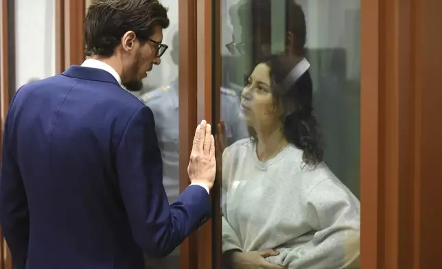 Ksenia Karelina, also known as Khavana speaks with her lawyer standing in a glass cage in a court room in Yekaterinburg, Russia, Thursday, Aug. 15, 2024. A Russian court on Thursday sentenced U.S.-Russian dual national Ksenia Khavana to 12 years in prison on a treason conviction for allegedly raising money for the Ukrainian military. (AP Photo)