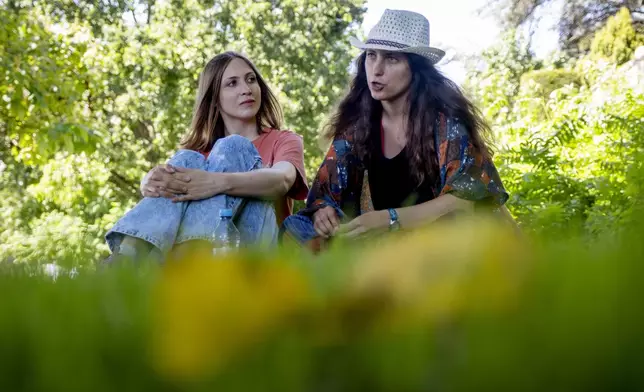 Freed Russian artist Sasha Skochilenko, right and her partner, Sofya Subbotina, sit on the grass in a park in Koblenz, Germany, Saturday, Aug. 10, 2024. (AP Photo/Michael Probst)