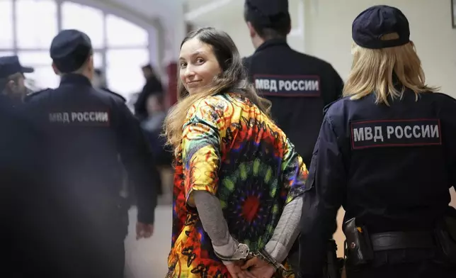 FILE - Sasha Skochilenko, a 33-year-old artist and musician, walks escorted by officers to court for a hearing in St. Petersburg, Russia, on Oct. 19, 2023. Skochilenko was arrested in April 2022 on the charges of spreading false information about the military after replacing supermarket price tags with messages about the Russian action in Ukraine. (AP Photo/Dmitri Lovetsky, File)