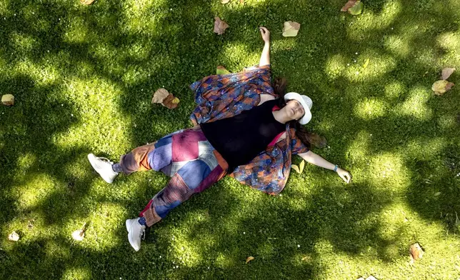 Russian artist Sasha Skochilenko, freed in a prisoner swap this month, relaxes on the grass in a park in Koblenz, Germany, Saturday, Aug. 10, 2024. (AP Photo/Michael Probst)